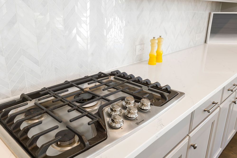 White chevron kitchen backsplash over gas cooktop